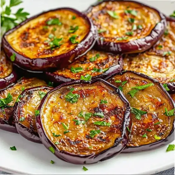 us1-eggplant-recipes-20250607-133536 Tender golden sauteed eggplant slices garnished with fresh parsley on a white platter